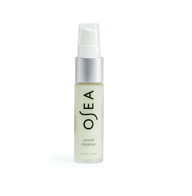 A small, clear bottle of OSEAs Ocean Cleanser with a white pump is infused with organic seaweed and lactic acid. The label has black text on a light background, set against a plain white backdrop.