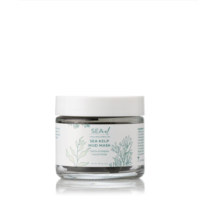A clear glass jar labeled Sea-el Sea Kelp Mud Mask sits on a white background with green botanical illustrations, containing gray facial mask enriched with purifying clays and ocean minerals, and finished with a white lid.