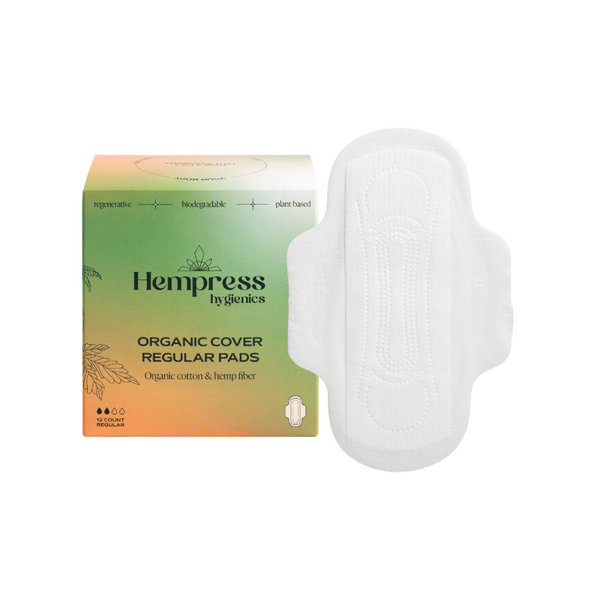 A box of Hempress Hygienics Hemp Regular Pads with a hypoallergenic white pad beside it. The green and orange box highlights that the pads are biodegradable, plant-based, and made with organic cotton and pesticide-free hemp fiber.