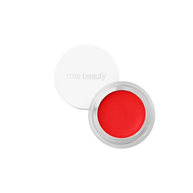 A small, partially open RMS Beauty Lip2cheek with a white lid reveals vibrant red cream blush, rich in wildcrafted buriti oil, on a white background.
