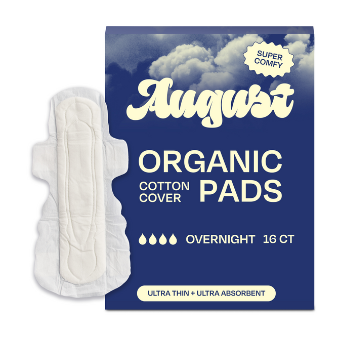 A box of August Long Night Pads sits next to a super absorbent night pad. The blue packaging with cloud imagery reads Super Comfy, Overnight 16 ct, and Ultra Thin + Ultra Absorbent hypoallergenic sanitary pads.
