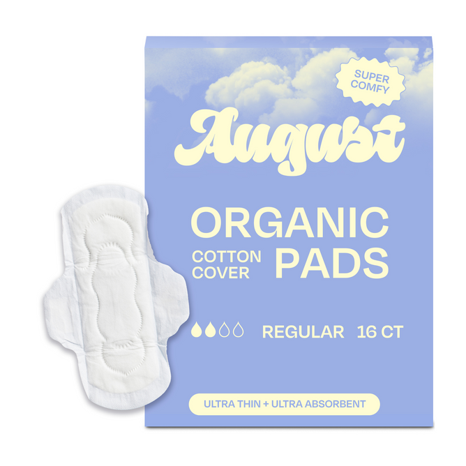 A blue August Day Pad box labeled Organic Cotton Cover with Regular 16 CT and an image of an ultra-thin, white pad. These hypoallergenic cotton pads are super absorbent, featuring clouds and the text: Super Comfy, Ultra Thin.