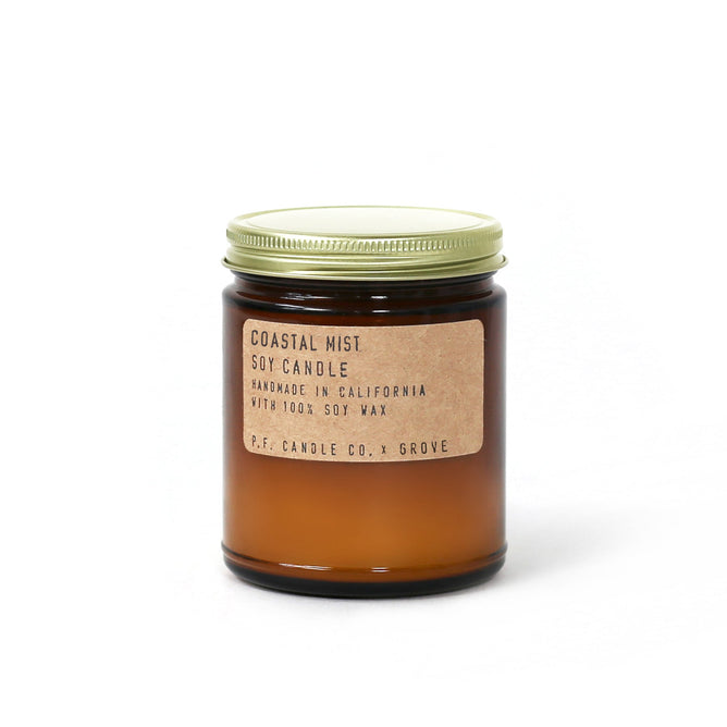 The Coastal Mist Soy Candle - Grove x P.F. Candle Co. Exclusive is housed in a brown glass jar with a metal lid. Handmade in California from 100% soy wax, it captures the essence of the California coastline experience.