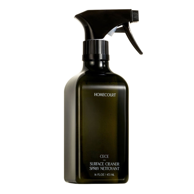 A black spray bottle labeled Homecourt Surface Cleaner, 16 fl. oz. / 473 ml, with fine fragrance and skin-safe ingredients, is shown against a white background.