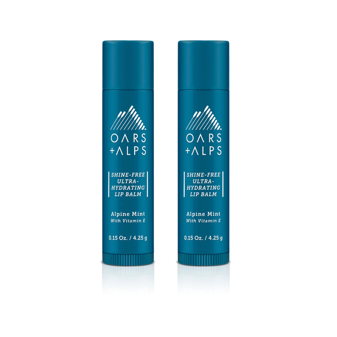 Two blue tubes of Oars + Alps Shine-Free Lip Balm in Alpine Mint scent, enriched with Vitamin E. Each 0.15 oz organic tube features a mountain and logo on a white background.