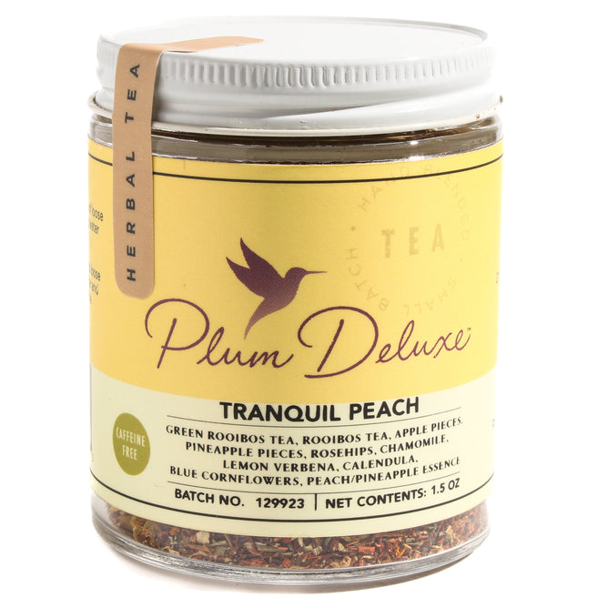 A jar of Plum Deluxe Tranquil Peach Tea, a caffeine-free blend with rooibos, apple pieces, pineapple, rosehips, chamomile, lemon verbena, calendula, and blue cornflowers.