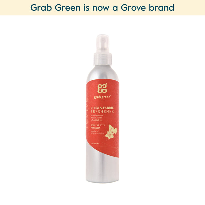 A silver spray bottle of grab green Room and Fabric Freshener – Red Pear with Magnolia (Coming Soon!) with a red floral label, shown on a white background. Text above reads, grab green is now a Grove brand. Great for neutralizing odors in any space.
