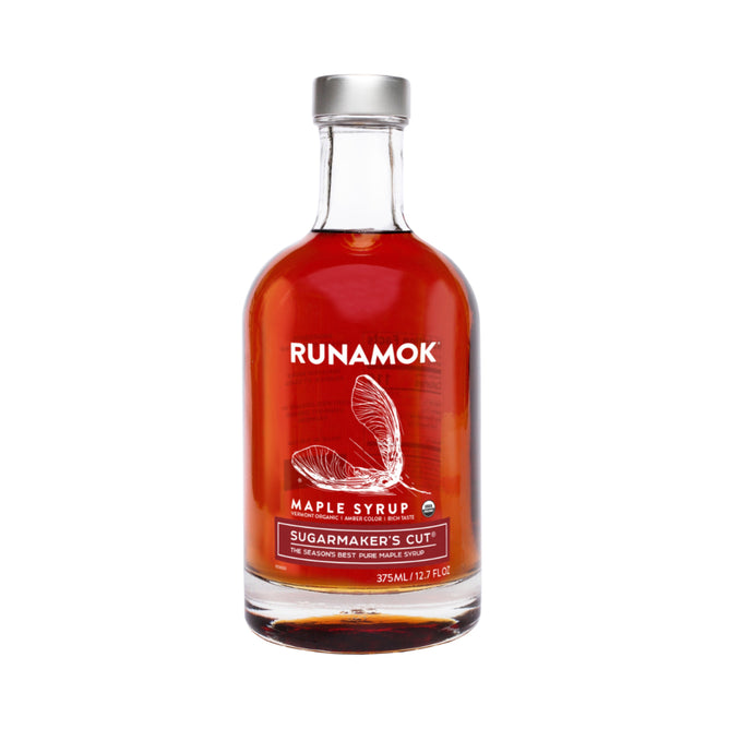 A clear glass 375ml bottle of Runamok Sugarmakers Cut Maple Syrup, with a maple seed illustration on the label. This amber syrup is harvested during sugaring season and certified organic.