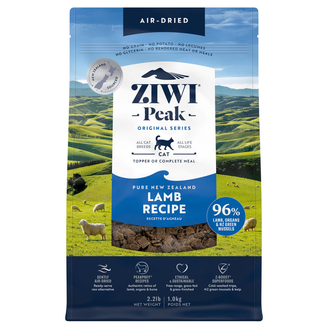 A bag of ZIWI Air-Dried Cat Food—All Natural, High Protein, Grain Free, Limited Ingredient with Superfoods—rests against New Zealand hills, its blue and white packaging highlighting it as a wholesome raw cat food alternative.