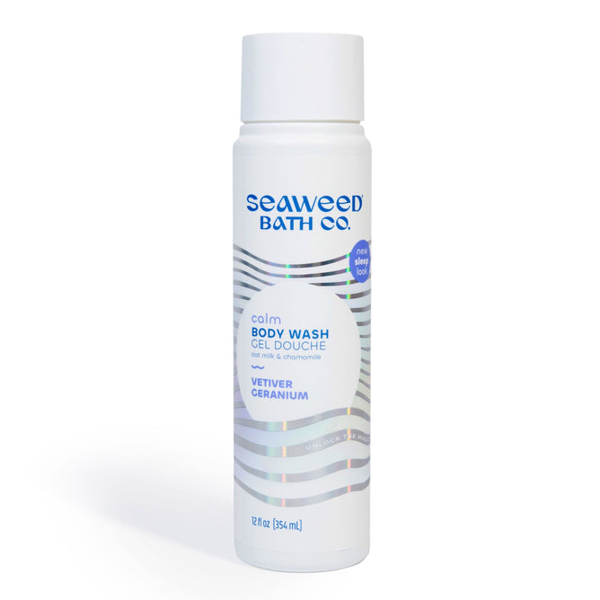 A 12 fl oz cylindrical bottle of The Seaweed Bath Co. Calm Body Wash with soothing chamomile, vetiver, geranium, nourishing Atlantic seaweed; design features blue text on white with wavy silver lines.