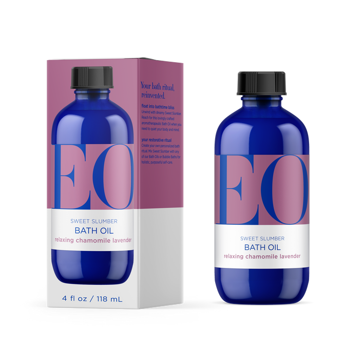 A blue bottle of EO Products Bath Oil with soothing lavender and calming chamomile sits beside its matching box. Both feature pink and blue accents on their labels, highlighting aromatherapeutic benefits for relaxation and revitalization.