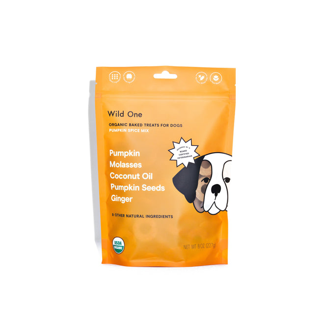 The Wild One Organic Pumpkin Spice Mix Baked Dog Treats come in an orange bag. Formulated with a veterinary nutritionist, they include pumpkin, molasses, coconut oil, pumpkin seeds, and ginger. The package features a charming cartoon dog graphic on the side.