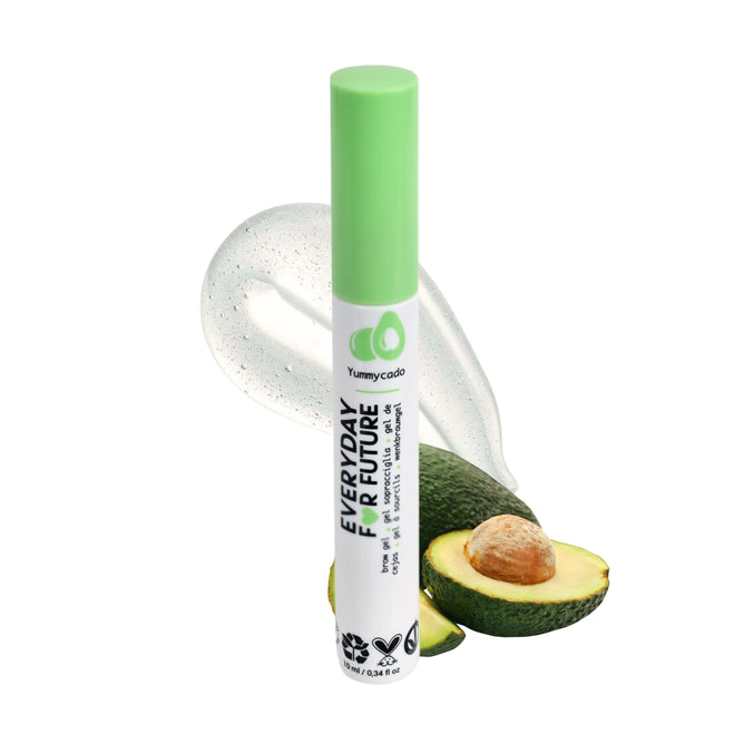 A Clear Avocado Brow Gel tube by Everyday For Future stands upright with a green cap. Avocados and a clear gel surround it, with the packaging showcasing avocado graphics and eco-friendly icons, emphasizing its vegan and cruelty-free commitment.