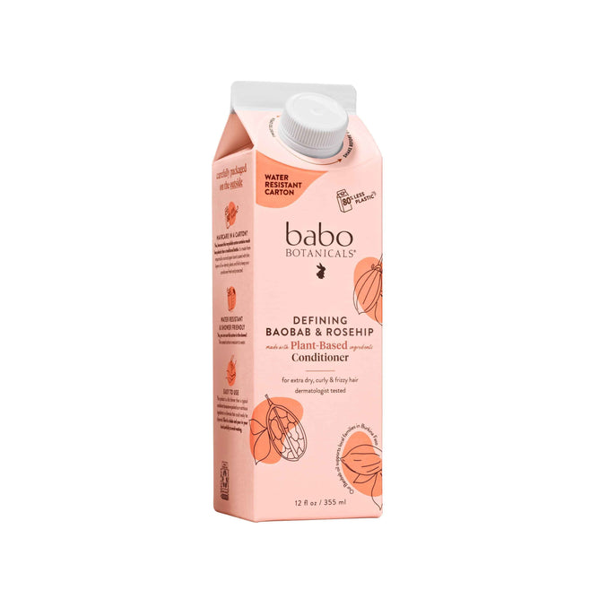 Babo Botanicals Defining Baobab & Rosehip Conditioner, in a pink carton with a white cap, tames frizz for curly, dry hair. The plant-based vegan formula comes in sustainable, water-resistant packaging and contains 12 fl oz (355 ml).