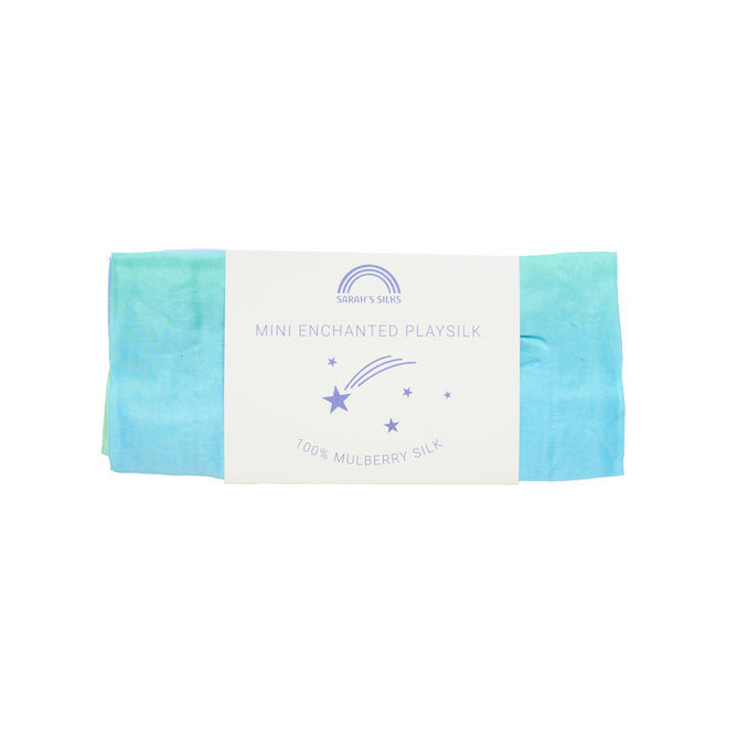 A folded blue and green playsilk for open-ended play is elegantly wrapped with a label featuring a rainbow design, stars, and planets. It reads Sarahs Silks Mini Playsilk for Open-Ended, Imaginative Play and boasts 100% pure mulberry silk.