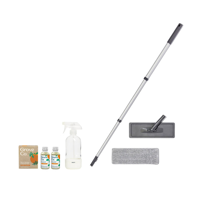A cleaning kit called the Floor Cleaning Starter Set by Grove Collaborative includes a gray microfiber mop with a long handle and flat head, a spray bottle, two small floor cleaner bottles, and comes in an Grove Co. box with orange illustrations.