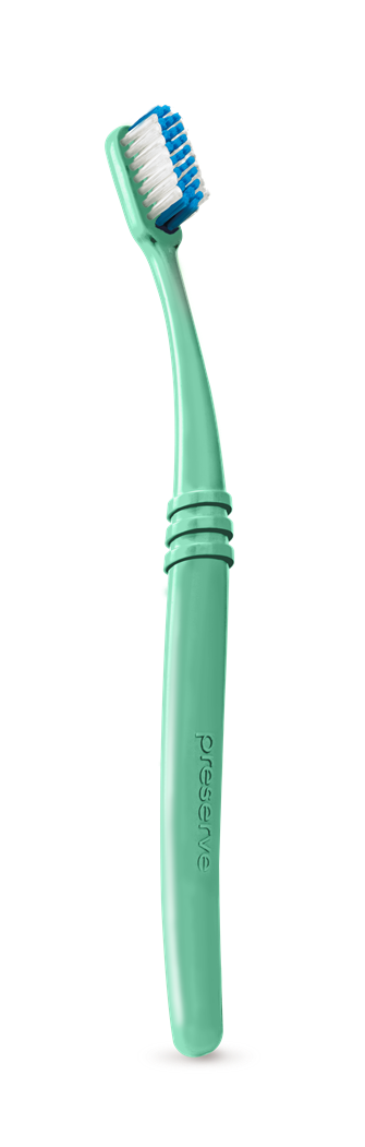 A green toothbrush from Preserve, made with recycled ocean plastic, features a curved handle with textured grip and white bristles with blue tips. Recycled Ocean Plastic Toothbrush (Soft) is proudly embossed on the handle.