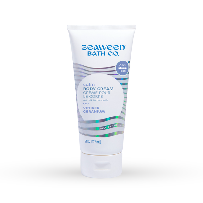 A 6 fl oz (177 ml) tube of The Seaweed Bath Cos Calm Body Cream, enriched with oat milk, vetiver, and geranium. It features white packaging with blue text and silver waves, labeled new sleep look to emphasize its calming effects.
