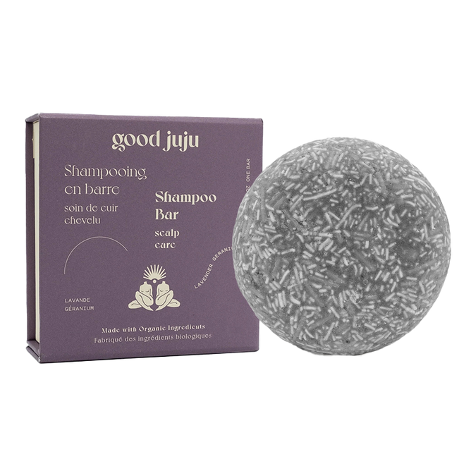 A round, textured Scalp Care Shampoo Bar with a purple box featuring Good Juju Body & Home branding and floral designs, displaying Shampoo Bar in English and French. It highlights the use of organic botanicals for scalp care.