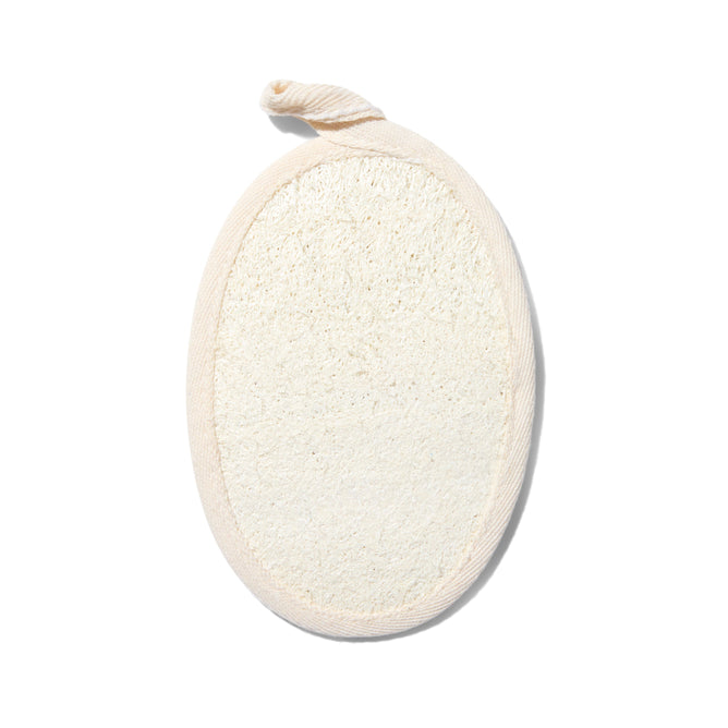 The Exfoliating Loofah Pad by Grove Co. is a beige, oval-shaped pad made from natural plant fibers, featuring a fabric edge and hanging loop. Its textured surface is perfect for gentle skin exfoliation, while the pristine white background underscores its simplicity and eco-friendly appeal.