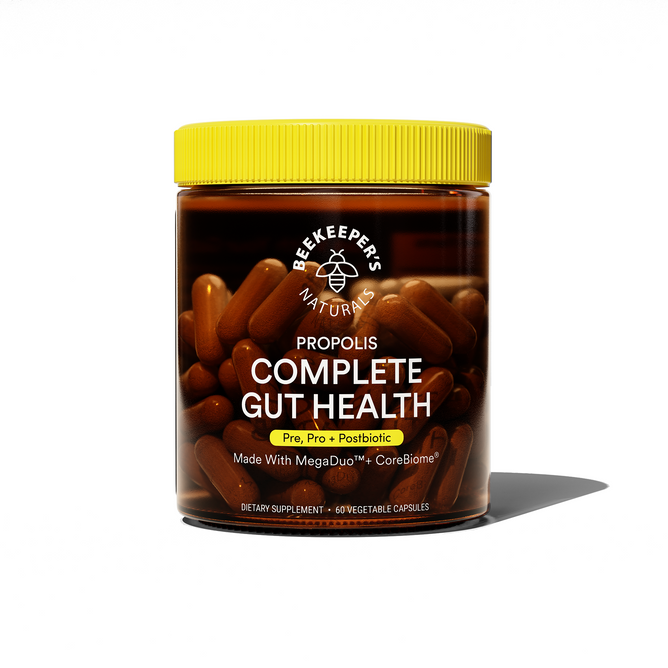 A clear jar of Beekeepers Naturals 3-in-1 Complete Gut Health showcases its propolis-based capsules. The label highlights Pre, Pro + Postbiotic with MegaDuo and CoreBiome for digestive balance. Contains 60 vegetable capsules with a yellow lid inside the transparent container.