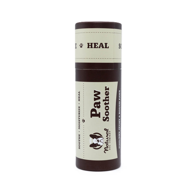 The Natural Dog Company’s Paw Soother comes in a cylindrical container for dogs, with dark brown and cream packaging displaying text like Paw Soother, Soothes, Moisturizes, Heals, and features a dog illustration.