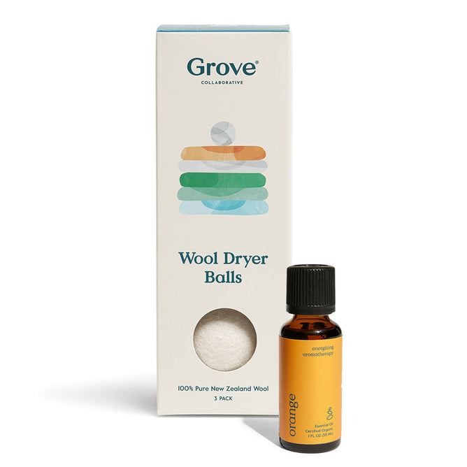 A box marked Grove Co. Wool Dryer Balls + Orange Essential Oil is beside a small orange bottle labeled energizing natural essential oils with the scent orange. The box states its 100% pure New Zealand wool content and includes three dryer balls.