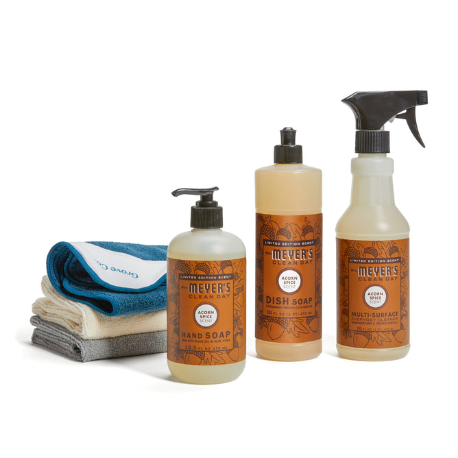 The Mrs. Meyers Fall Cleaning Set features hand soap, dish soap, and multi-surface spray alongside four folded cleaning cloths in white, blue, and gray, all displayed against a white background.