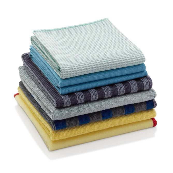 The E-Cloth Home Cleaning Set includes six neatly stacked folded kitchen towels in colors like light blue, dark blue, mustard yellow, yellow, and gray stripes. Each towel features different textures and fabric weaves.