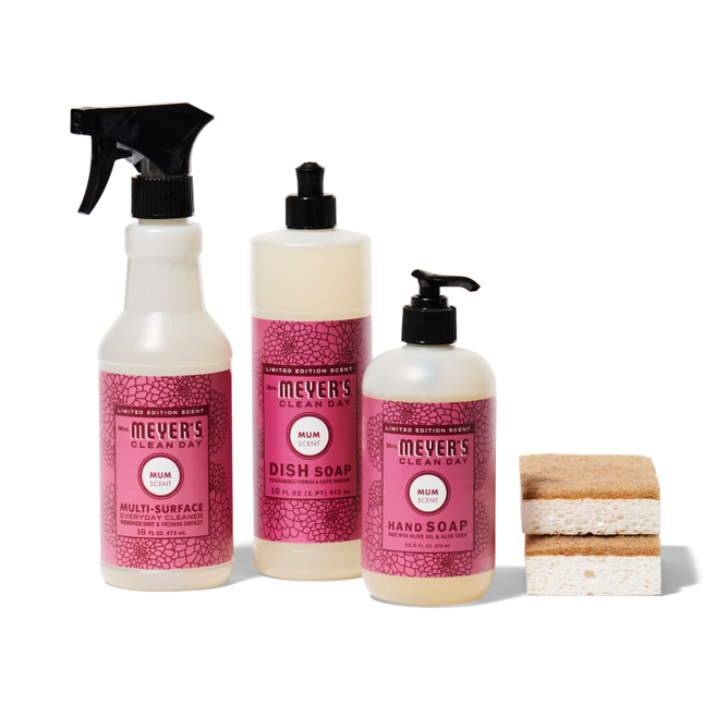 Three pink-labeled bottles from the Grove Collaborative Happy Harvest Essentials Set: a multi-surface spray, dish soap, and hand soap. Next to them are two stacked sponges on a white background.