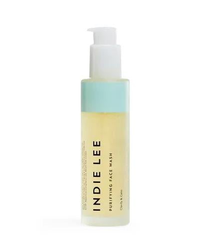 The Indie Lee Purifying Face Wash comes in a clear pump bottle with a light blue label and black text, featuring an antioxidant-rich formula. It contains a light yellow liquid and is showcased against a pristine white background.