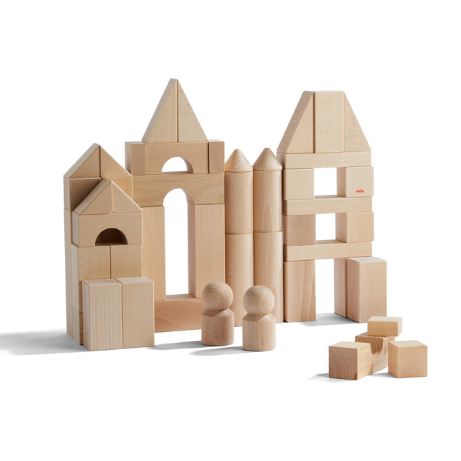 The HABA Basic Building Blocks - Large Starter Set allows children to construct a castle-like structure with arches and cylindrical towers. Two peg people stand guard while unattached blocks lie nearby, fostering imagination and promoting development through sustainable play.