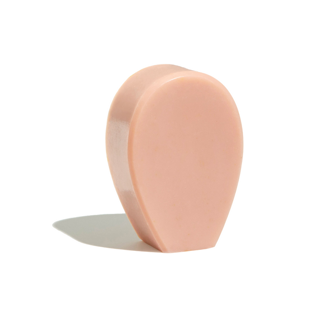 NOPALERAs Cactus Bar Soap, a pink teardrop-shaped bar with a smooth surface, stands upright against a plain white background, casting a small shadow to the left.