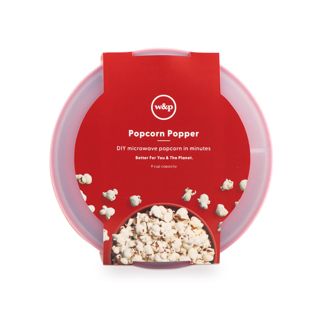 The W&P Reusable Popcorn Popper is a red and clear plastic bowl packaged with a cardboard sleeve, featuring the w&p Popcorn Popper text and a popped popcorn image. It holds up to 9 cups, is dishwasher-safe, and offers DIY microwave popcorn in minutes.