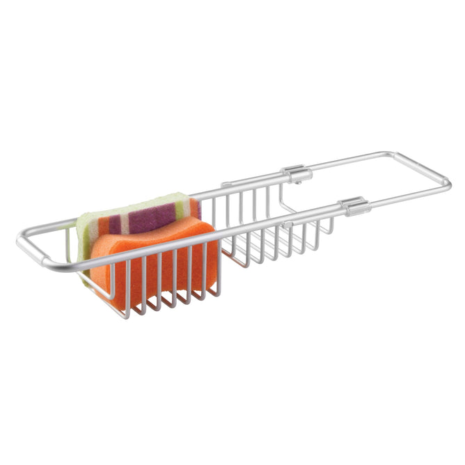 The iDesign Aluminum Over The Sink Basket, with a grid design, holds an orange sponge and folded striped washcloth. Made from rust-resistant aluminum, it features an extendable arm for adjusting to different tub sizes, ensuring durability and perfect fit.