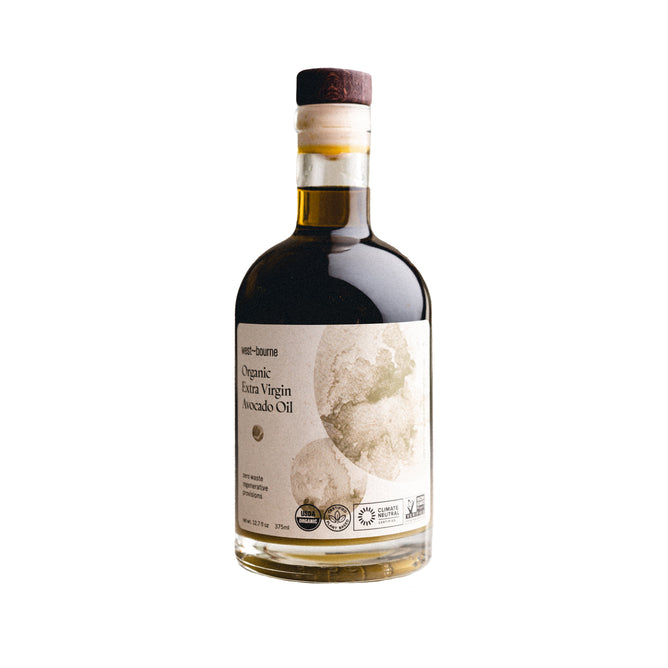 The Organic Extra Virgin Avocado Oil by west~bourne comes in a clear bottle with a dark cap and an avocado-designed label. Its ideal for high heat cooking, displaying its rich color, while certification icons ensure it supports a sustainable kitchen.