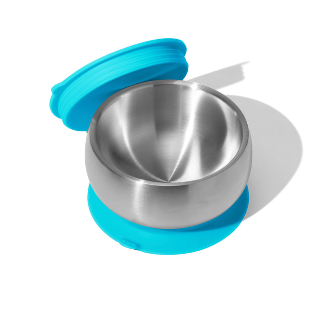 Viewed from above, an Avanchy Stainless Steel Baby Suction Bowl with a blue lid and matching base casts a shadow on the white background. The eco-friendly lid is partially off and placed beside the empty bowl.