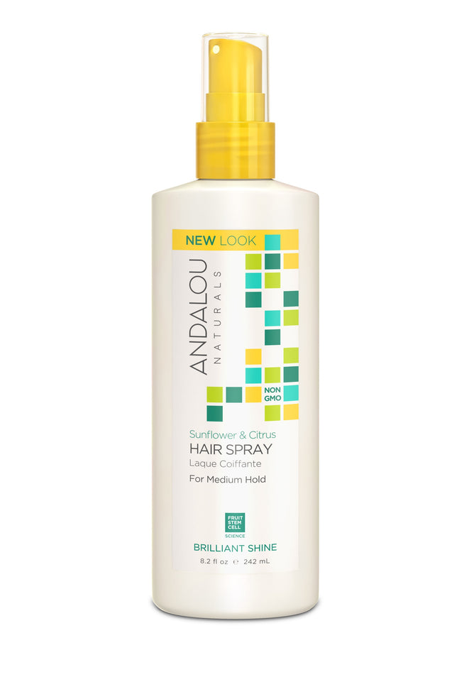The Brilliant Shine Sunflower & Citrus Hair Spray by Andalou Naturals features a white bottle with a yellow spray nozzle and geometric design, promoting non-GMO, vitamin C, and fruit stem cell science for nourishment, offering medium hold in an 8.2 fl oz (242 ml) volume.