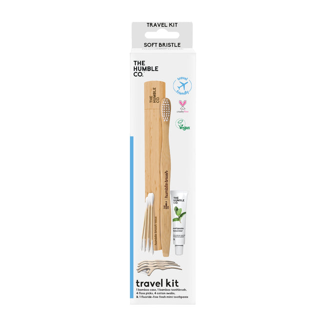 The Oral-Care Travel Kit from The Humble Co. highlights a bamboo toothbrush, toothpaste, and plant-based floss picks in eco-friendly packaging. Adorned with vegan and cruelty-free icons, the box uses recycled materials and prominently features Soft Bristle at the top.