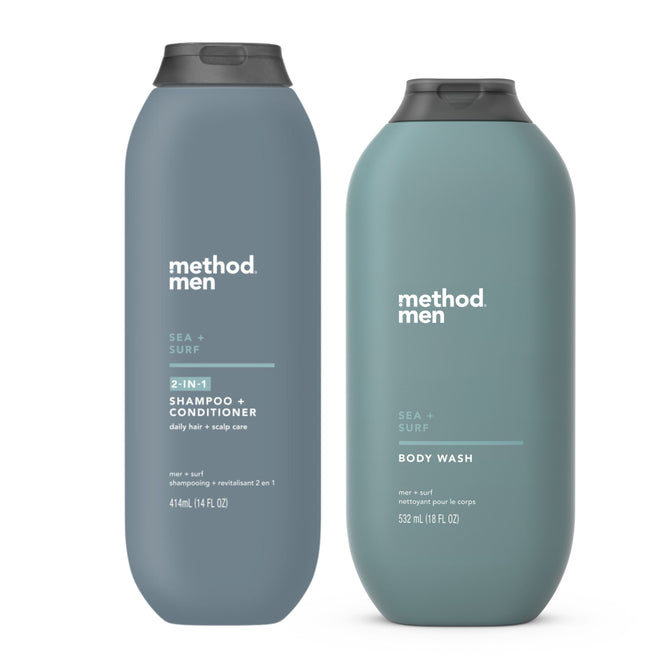 The stylish gray-blue Method Men bottles showcase the Body Set, featuring the Sea + Surf 2-in-1 Shampoo + Conditioner on the left and matching body wash on the right, embodying contemporary design and oceanic freshness.