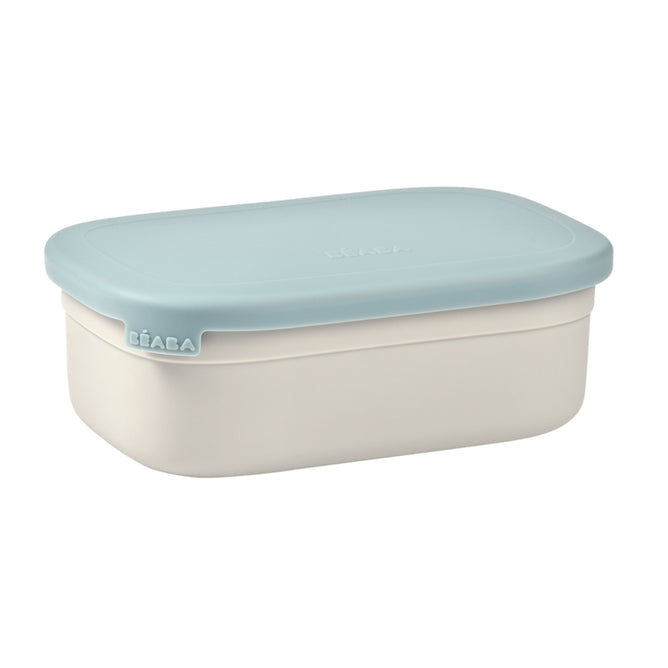 A BEABA Stainless Steel Bento Lunch Box featuring a rectangular design with light blue lid and white eco-friendly body. The fitted lid has silicone dividers, and the brand name is subtly embossed on both the lid and side.