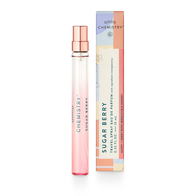A slender glass Eau De Parfum Travel Spray bottle from Good Chemistry, labeled Sugar Berry, features a gradient pink design beside a colorful box. The boxs abstract floral patterns and text highlight this vegan fragrance infused with essential oils.