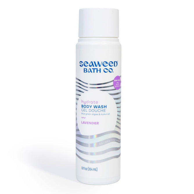 A 12 fl oz (354 ml) bottle of The Seaweed Bath Co.s Hydrating Body Wash, perfect for sensitive skin, features a blend of bladderwrack seaweed and kukui oil with a calming lavender scent. Its packaging is adorned with wavy silver lines and purple and black text.