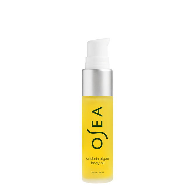 A transparent cylindrical bottle of OSEAs Undaria Algae Body Oil, featuring a pump dispenser, reveals its yellow seaweed-infused contents. The black label text enhances the organic botanical essence theme.