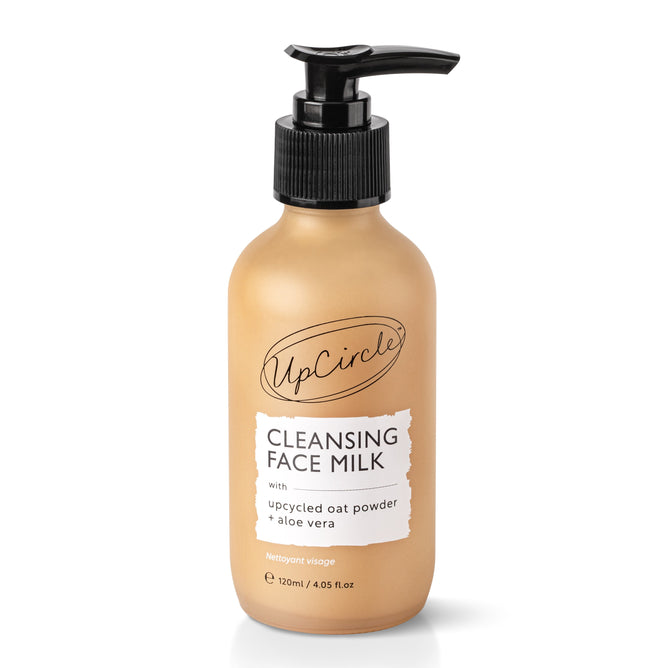 A beige, 120ml UpCircle Cleansing Face Milk includes a black pump and highlights its vegan formula on the label reading with upcycled oat powder & aloe vera, set against a white background.