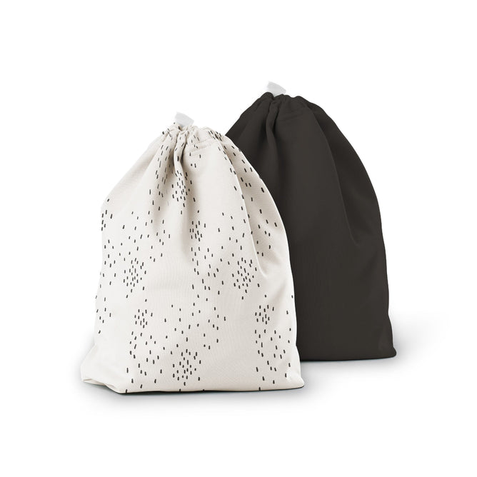 The Ditty Bag Duo Wet Bags by Esembly Baby are displayed. The left bag, made from recycled plastic, showcases small black dots on white, and the right one is solid black. Both bags stand upright against a plain white background.